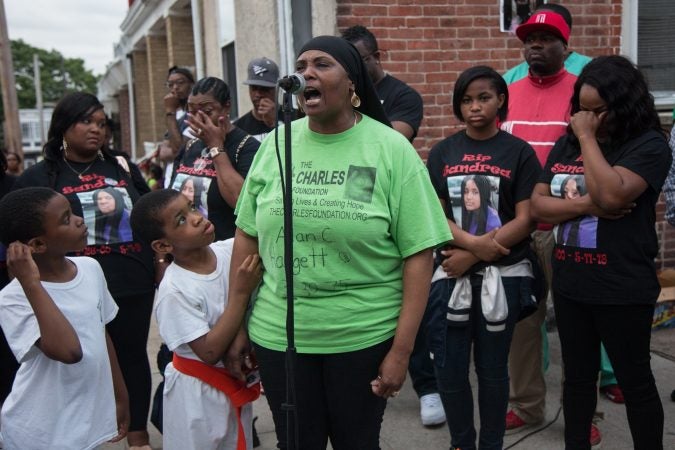 Movita Johnson-Harrell gives an impassioned speech about the need for change in the foundations of the African-American communities of Philadelphia citing the murder of her son, a victim of random gun violence. By her side stands her grandson who was born just weeks after his father, her son, had been killed. (Emily Cohen for WHYY)