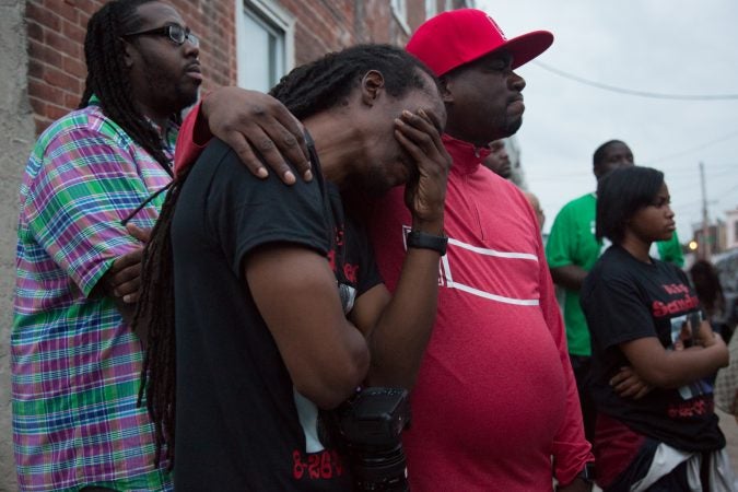 Marlando Powell finds comfort in a community member at a vigil for his 17 year old niece Sandrea Williams three weeks after she was shot and killed in a random act of gun violence in front of her mother’s home. The vigil doubled as a rally to bring justice to her family. (Emily Cohen for WHYY)