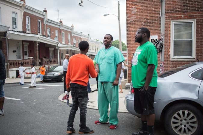 Amir hosendorf, who works at St Christopher's Hospital and lives in neighborhood, greets a friend at the rally bring justice for the death of 17 year old Sandrea Williams three weeks after she was gunned down in a random act of violence outside of her mother’s in their West Philadelphia home on May 11th 2018. (Emily Cohen for WHYY)