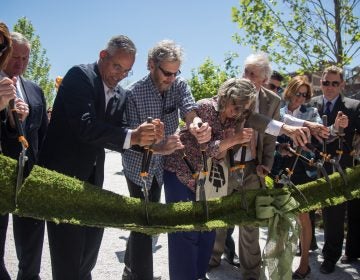 Integral members of the team that brought the rail park to life, including Sarah McEneaney (center) and John Struble (center left), cut the “green” ribbon, officially opening the first quarter mile of the Philadelphia Rail Park June 14th 2018. (Emily Cohen for WHYY)
