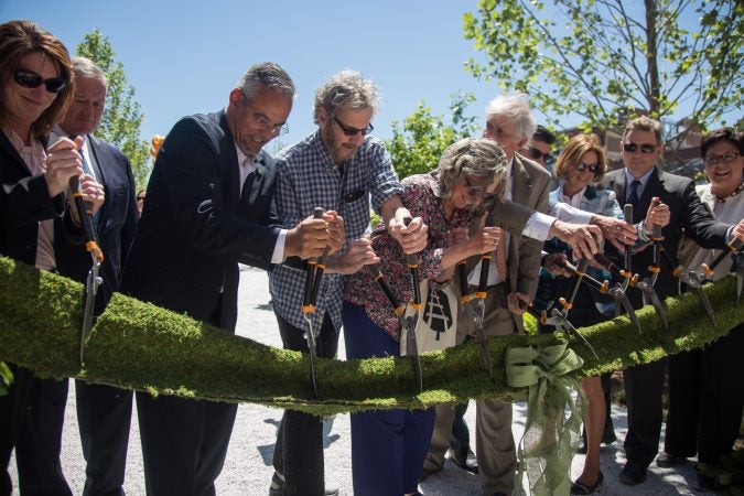 Integral members of the team that brought the rail park to life, including Sarah McEneaney (center) and John Struble (center left), cut the “green” ribbon, officially opening the first quarter mile of the Philadelphia Rail Park June 14th 2018. (Emily Cohen for WHYY)