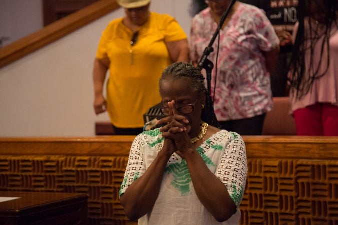 A member of the chorus bows her head as a prayer is said before the choir’s final rehearsal begins. (Emily Cohen for WHYY)