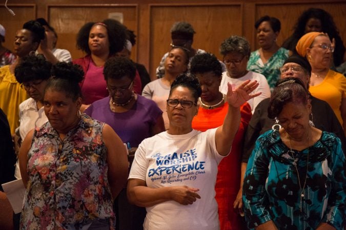 Members of the chorus bow their heads in prayer as one is said at the beginning of their final rehearsal. (Emily Cohen for WHYY)