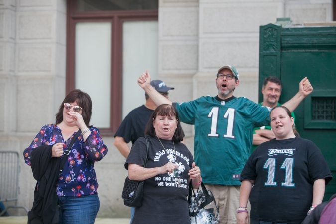 Mary Velez, (center), her daughter Elen, (right), and other Eagles fans sing the team's fight song at a rally for the team at City Hall Tuesday evening a day after President Trump canceled an event at the White House to honor the Super Bowl Champions. (Brad Larrison for WHYY)