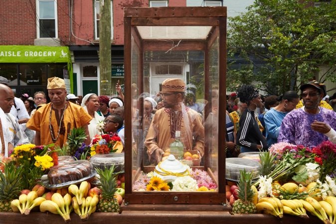 The procession at the 2018 Odunde Festival in South Philadelphia is led with a cart of offerings including fresh fruit, flowers, cakes, and other biodegradable goods. (Natalie Piserchio for WHYY News) 