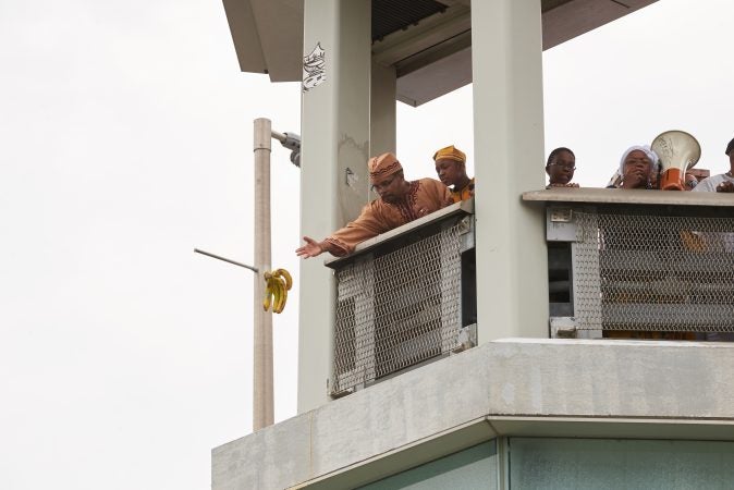 Sehemeh Burke, a priest of Osun in the Lukumi tradition, casts a hand of bananas into the Schuylkill River as offerings to Osun, the Yoruba goddess of the river. (Natalie Piserchio for WHYY News) 