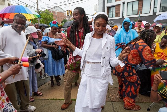 Fo’la’mi and Farugh dance a mix of West African on the corner of 23rd and Bainbridge streets as it begins to rain at the Odunde Festival on Sunday, June 10, 2018. Attendees of the festival play Djembe and other percussion instruments. (Natalie Piserchio for WHYY News) 