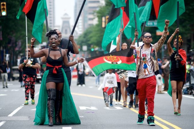 Leighdy Morris, Queen of the RBG brigade (left) raises a fist as she marches on Market Street during the annual Juneteenth Parade, on Saturday. (Bastiaan Slabbers for WHYY)