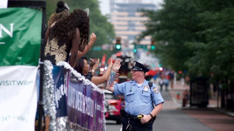 A police officer mimics the waving hand gestures of young women on a float during the Juneteenth Parade, in Center City, on Saturday. (Bastiaan Slabbers for WHYY)