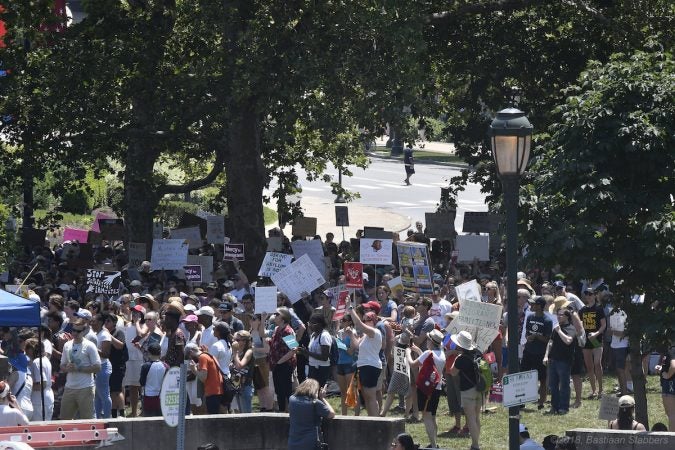 Protesters find shade under the trees as they listen to speakers during a rally against immigrant family detention, at Logan Square, on Saturday. (Bastiaan Slabbers for WHYY)