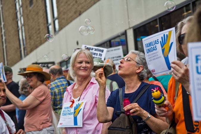 Amy Trachtenberg blows bubbles outside of the Center City Philadelphia office of ICE  to protest the practice of separating children from their families. (Kimberly Paynter/WHYY)