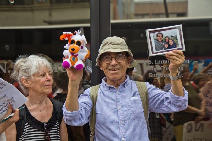 Ramon Garcia Castro holds up a photo of his family in Chile outside of the Center City offices of ICE to protest the practice of separating children from their families. (Kimberly Paynter/WHYY)