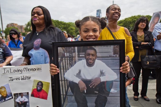 Kimora Ford, 10, holds a photograph of her stepfather, James Walke, to honor his memory at the demonstration against violence. (Kimberly Paynter/WHYY)