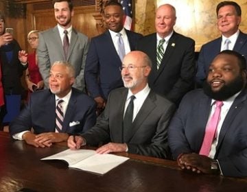 Philadelphia Senator Anthony Williams, Governor Tom Wolf, and Philadelphia Representative Jordan Harris pose for pictures after signing the Clean Slate bill. (Katie Meyer/WITF)