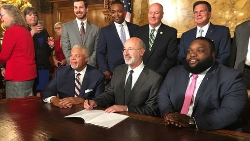 Philadelphia Senator Anthony Williams, Governor Tom Wolf, and Philadelphia Representative Jordan Harris pose for pictures after signing the Clean Slate bill. (Katie Meyer/WITF)