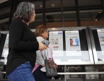 Newseum visitors browse newspaper front pages displayed outside the museum in Washington, Monday, June 11, 2018.