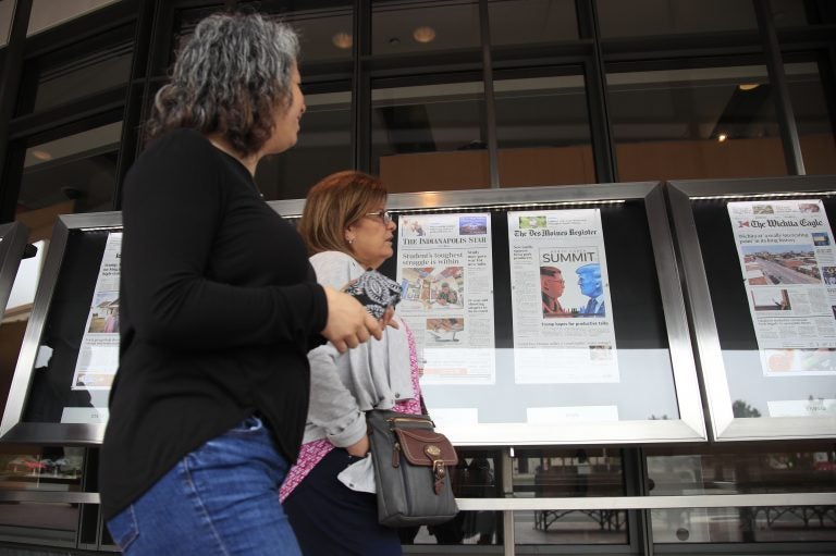 Newseum visitors browse newspaper front pages displayed outside the museum in Washington, Monday, June 11, 2018.