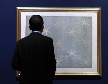 Assistant curator Matthew Skic looks the newly-hung Commander-in-Chief's Standard, Wednesday, June 13, 2018, at the Museum of the American Revolution in Philadelphia. The faded and fragile blue silk flag marked General George Washington's presence on the battlefield during the Revolutionary War. The museum is bringing the flag out of its archives for public viewing on Thursday, June 14, Flag Day, until Sunday. Its appearance at the museum is the flag's first public display in Philadelphia since the war. (Jacqueline Larma/AP Photo)