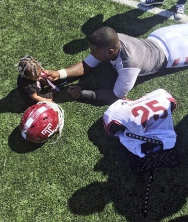 In this 2016 photo, Temple running back Ryquell Armstead plays on the field with his daughter Ry-kail during spring NCAA college football practice in Philadelphia. David Hood and  Armstead shared a position and an apartment while playing for Temple. They also shared the experience of being fathers on top of students and football players. (Tara Armstead via AP)
