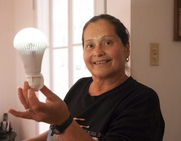 Minerva Ortolaza holds a rechargeable bulb her sister, Santa, uses to light her house. The Ortolazas didn't have light for months after Hurricane Maria hit Puerto Rico and they had to change their routines to make do. (Irina Zhorov/WHYY)