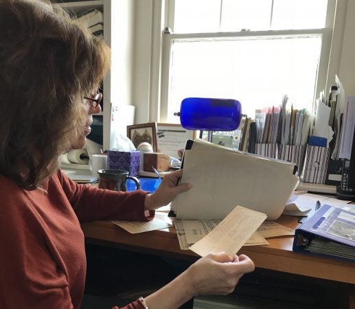 Judy Eidelson leafs through a folder of her father’s immigration documents. (Laura Benshoff/WHYY)