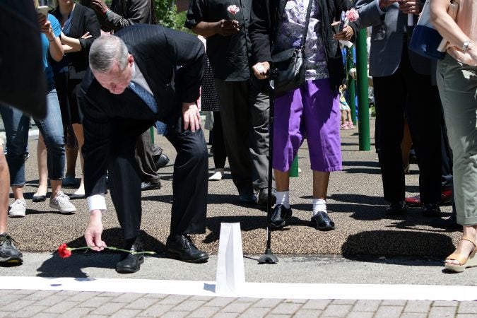 Major Jim Kenney, community members and elected officials place flowers on a symbolic border after the Philadelphia officially announces the development of Bethel Burying Ground Historic Site Memorial during a ceremony at Weccacoe Playground, in South Philadelphia, on Tuesday June 12, 2018. (Bastiaan Slabbers for WHYY)
