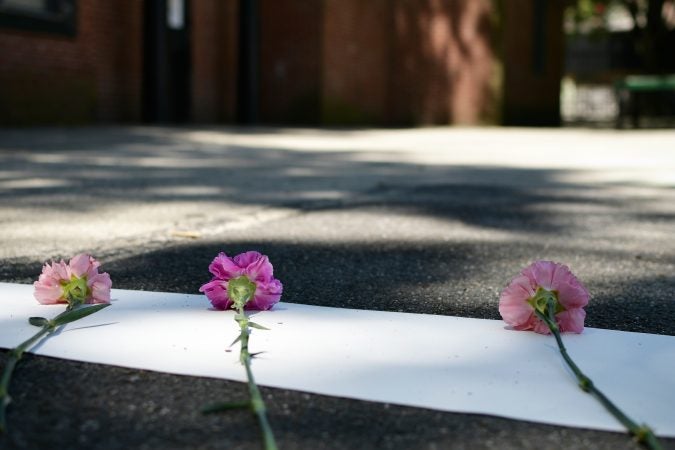 Community members and elected officials place flowers on a symbolic border after the Philadelphia officially announces the development of Bethel Burying Ground Historic Site Memorial during a ceremony at Weccacoe Playground, in South Philadelphia, on Tuesday June 12, 2018. (Bastiaan Slabbers for WHYY)