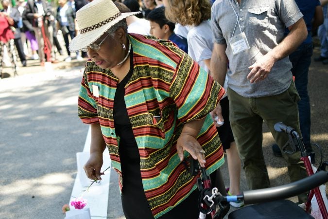 Community members and elected officials place flowers on a symbolic border after the Philadelphia officially announces the development of Bethel Burying Ground Historic Site Memorial during a ceremony at Weccacoe Playground, in South Philadelphia, on Tuesday June 12, 2018. (Bastiaan Slabbers for WHYY)