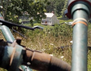 This July 27, 2011 file photo shows a farmhouse in the background framed by pipes connecting pumps where the hydraulic fracturing process in the Marcellus Shale was underway at a Range Resources site in Claysville, Pa. (Keith Srakocic/AP Photo)