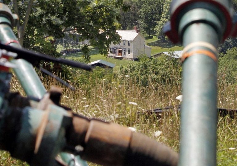 This July 27, 2011 file photo shows a farmhouse in the background framed by pipes connecting pumps where the hydraulic fracturing process in the Marcellus Shale was underway at a Range Resources site in Claysville, Pa. (Keith Srakocic/AP Photo)