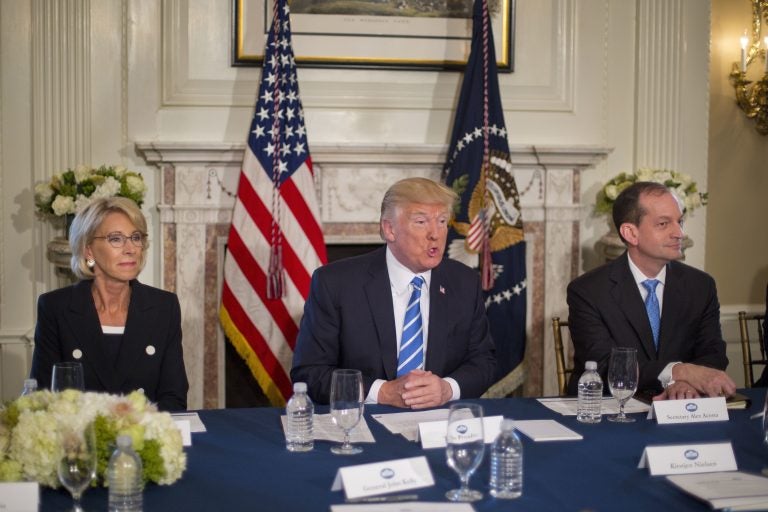 President Donald Trump, flanked by Education Secretary Betsy DeVos, (left), and Labor Secretary Alexander Acosta, answers questions in August of 2017, at Trump National Golf Club in Bedminster, N.J. Today the White House announced plans to merge the two departments. (Pablo Martinez Monsivais/AP)