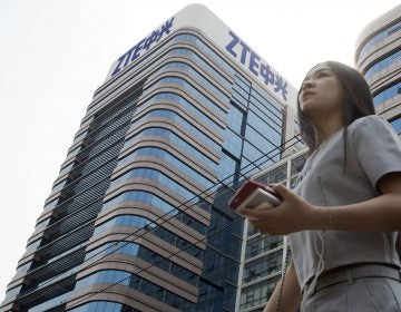 A woman passes by a ZTE building in Beijing, China shortly after President Donald Trump tweeted about possibly reversing a ban on the tech giant in May