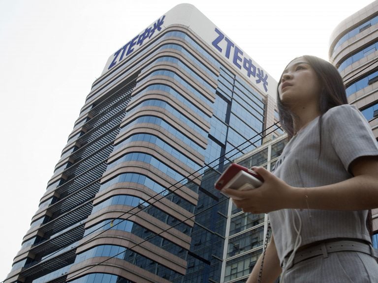 A woman passes by a ZTE building in Beijing, China shortly after President Donald Trump tweeted about possibly reversing a ban on the tech giant in May