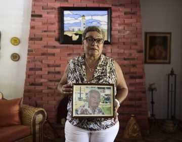 Puerto Rican Nerybelle Perez poses with a portrait of her father, World War II veteran Efrain Perez, who died after his ambulance was turned away from the island's largest public hospital when it had no electricity or water following Hurricane Maria. (Carlos Giusti/AP)