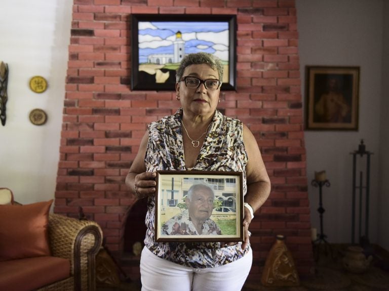 Puerto Rican Nerybelle Perez poses with a portrait of her father, World War II veteran Efrain Perez, who died after his ambulance was turned away from the island's largest public hospital when it had no electricity or water following Hurricane Maria. (Carlos Giusti/AP)