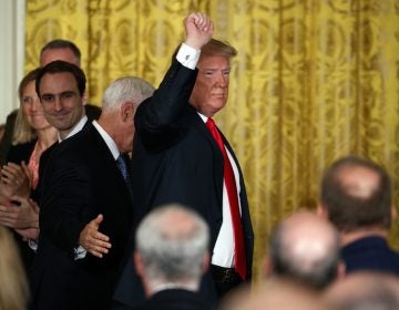 President Donald Trump pumps his fist as he leaves a meeting Monday in the East Room of the White House in Washington.