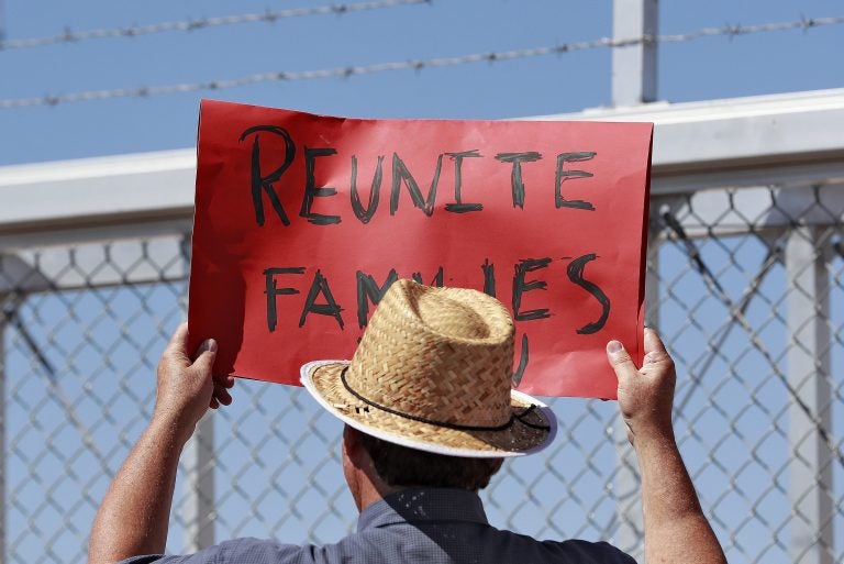 A protester holds a sign outside a closed gate at the Port of Entry facility, last week in Fabens, Texas, where tent shelters are being used to house separated family members.