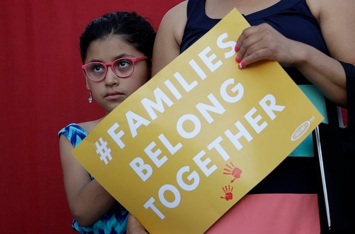 A girl stands with her mother during a Rally For Our Children event to protest a new 