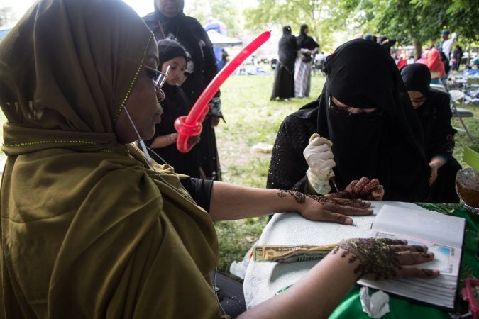 A woman recieves a henna tattoo at an Eid al-Fitr celebration, marking the end of Ramadan. (Kimberly Paynter/WHYY)