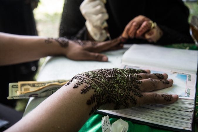 A woman recieves a henna tattoo at an Eid al-Fitr celebration, marking the end of Ramadan. (Kimberly Paynter/WHYY)