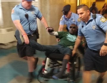 Philadelphia sheriff's deputies eject a protester from City Council chambers Thursday after he and others staged a die-in to protest a lack of housing for those with disabilities. (Tom MacDonald/WHYY)