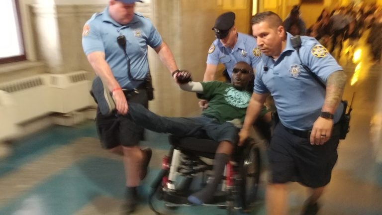 Philadelphia sheriff's deputies eject a protester from City Council chambers Thursday after he and others staged a die-in to protest a lack of housing for those with disabilities. (Tom MacDonald/WHYY)