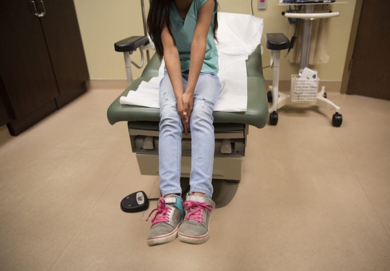 A young girl waits for care in a medical clinic. A growing number of citizen children of immigrant parents are losing out on Medicaid because their parents fear deportation. (Jonathan Kirn/Getty Images)