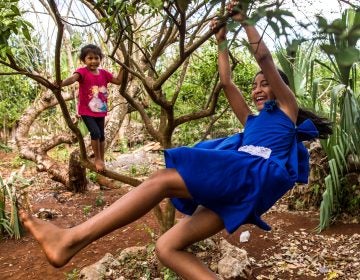 Gelmy, 9, and sister Alexa, 4, climbing trees in the backyard of their family home in the Yucatan Peninsula. (Adriana Zehbrauskas for NPR)
