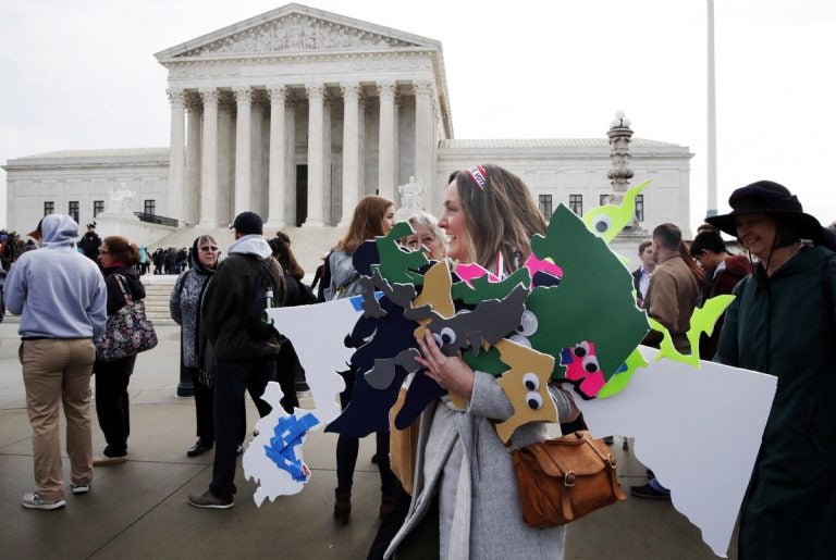 Ashley Oleson, with the League of Women Voters of Maryland, carries signs of the state's districts, before oral arguments in the Supreme Court in March.  (AP Photo/Jacquelyn Martin)