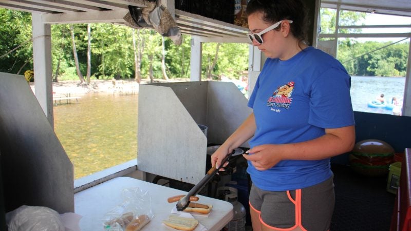 Amanda Nepton serves up some boiled hot dogs to customers who must wade up to the window. (Emma Lee/WHYY)