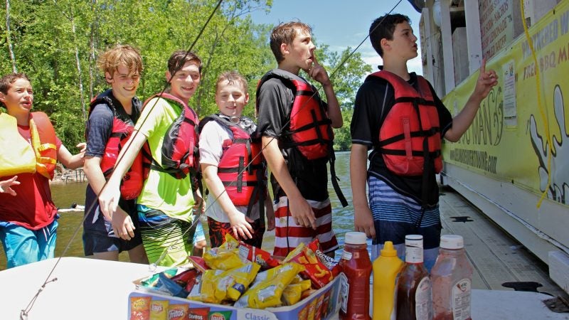 Jacob Tannenbaum (right), celebrating his 13th birthday with a tubing party, places his order at the Famous River Hot Dog Man. (Emma Lee/WHYY)