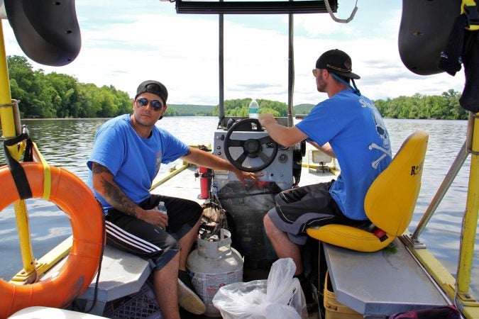 Mathew Crance and boat driver Nash Hughes head downriver toward the hot dog stand, loaded with tools and supplies. (Emma Lee/WHYY)