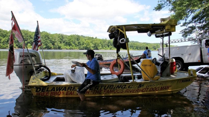 Mathew Crance loads a boat with supplies and heads to the hot dog stand, docked in the Delaware River off Adventure Island, which is owned by the Crance family. (Emma Lee/WHYY)