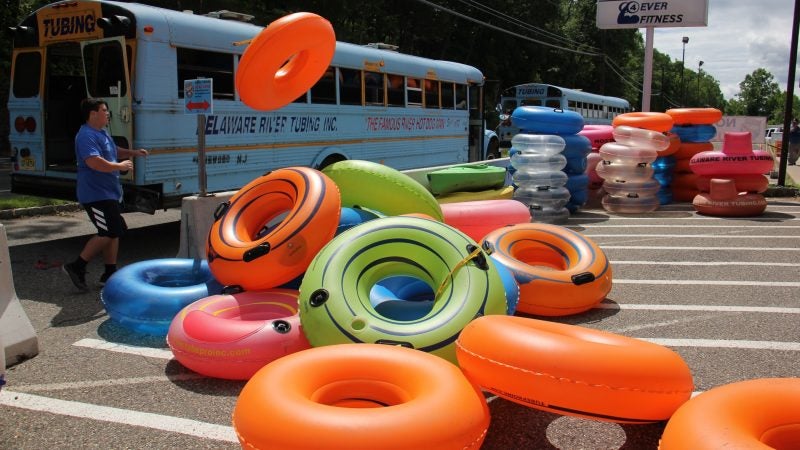 As the day begins at Delaware River Tubing, an employee unloads a bus full of tubes. (Emma Lee/WHYY)